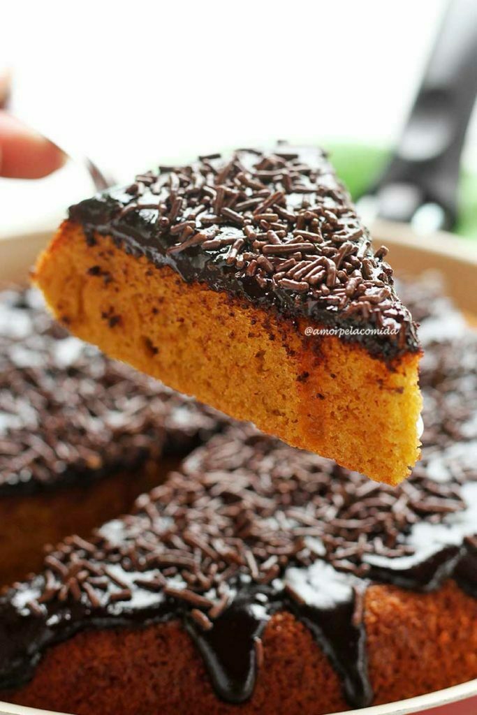 Pedaço de bolo de cenoura de frigideira sobre espátula, a frigideira com o restante do bolo está por baixo