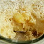 Travessa de vidro transparente cheia de sobremesa de abacaxi com coco e creme
